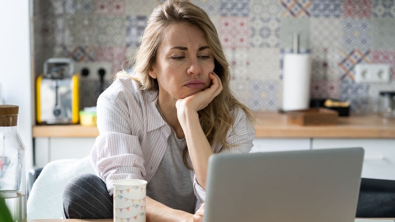 Woman looks concerned while looking at a laptop.